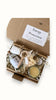 A gift box labeled 'Energy Protection' with various items including a bath salt, lip balm, sugar scrub, a dried flower, a bowl, a spoon, and a towel, all packaged with tissue paper and shredded paper for protection. Positive affirmation gifts, Christmas gift box and Spa gift set