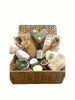Wicker basket with various items including a bottle, candle, Clay mask, Wellness Hamper UK, Pamper Hamper UK, Curated gift boxes