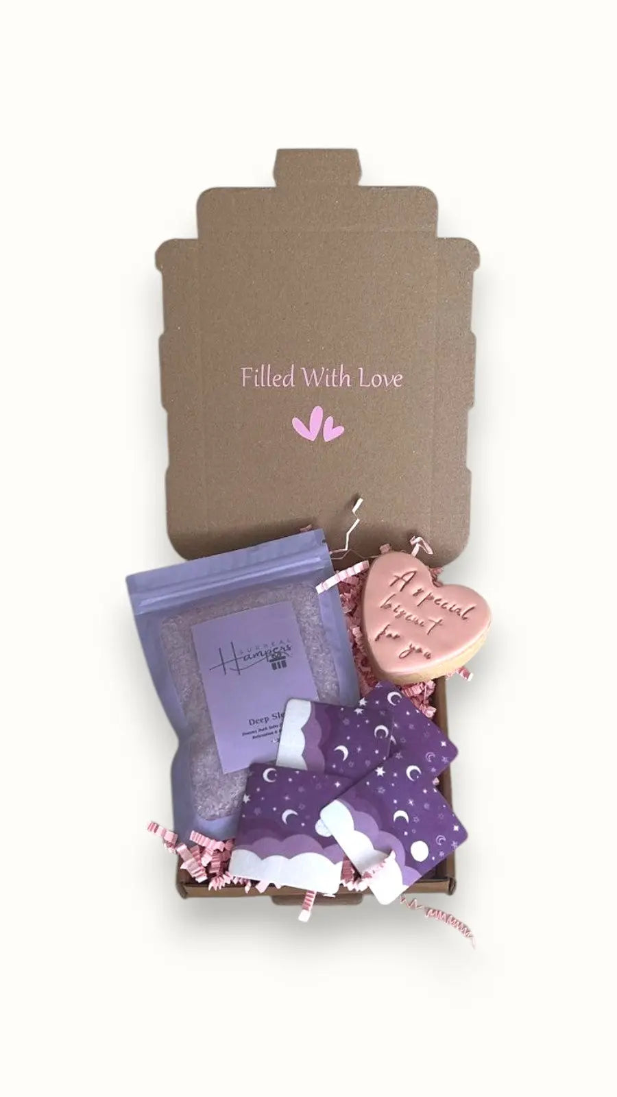 A gift box 'Filled With Love' Mini Christmas gift containing a package of Lavender bath salts, a special biscuit, and overnight patches.