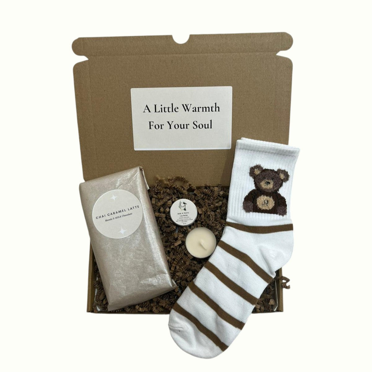 Mini gift box containing cosy socks, tealight candle, lip balm, and chai caramel chocolate, perfect pamper present for her or thoughtful small gift